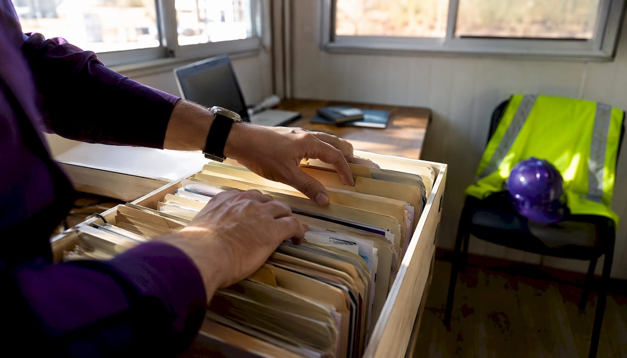 Hands filing WHS records in site office