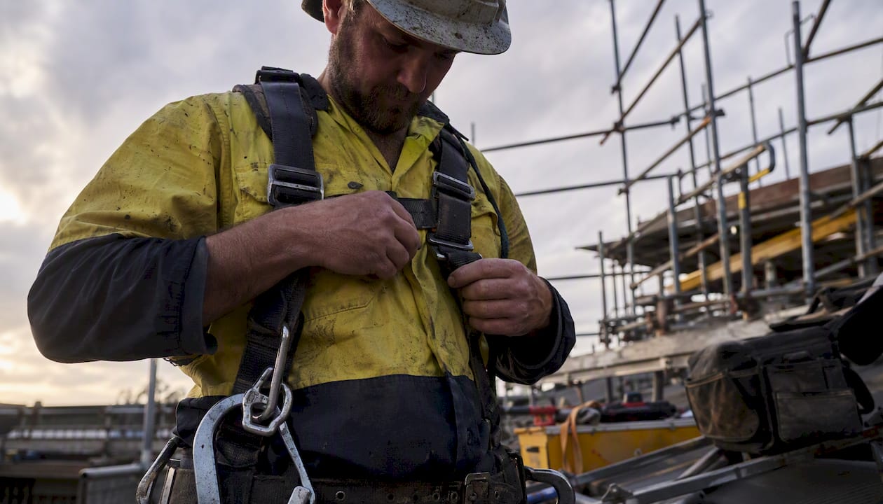 Tradie checking safety harness on worksite