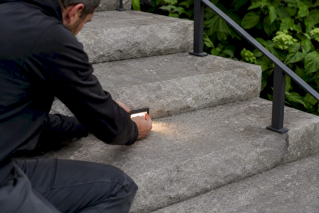 Hand installing recessed step light on stair tread