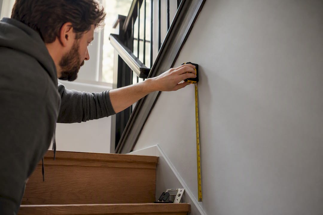 Hand measuring height above staircase tread for sconce