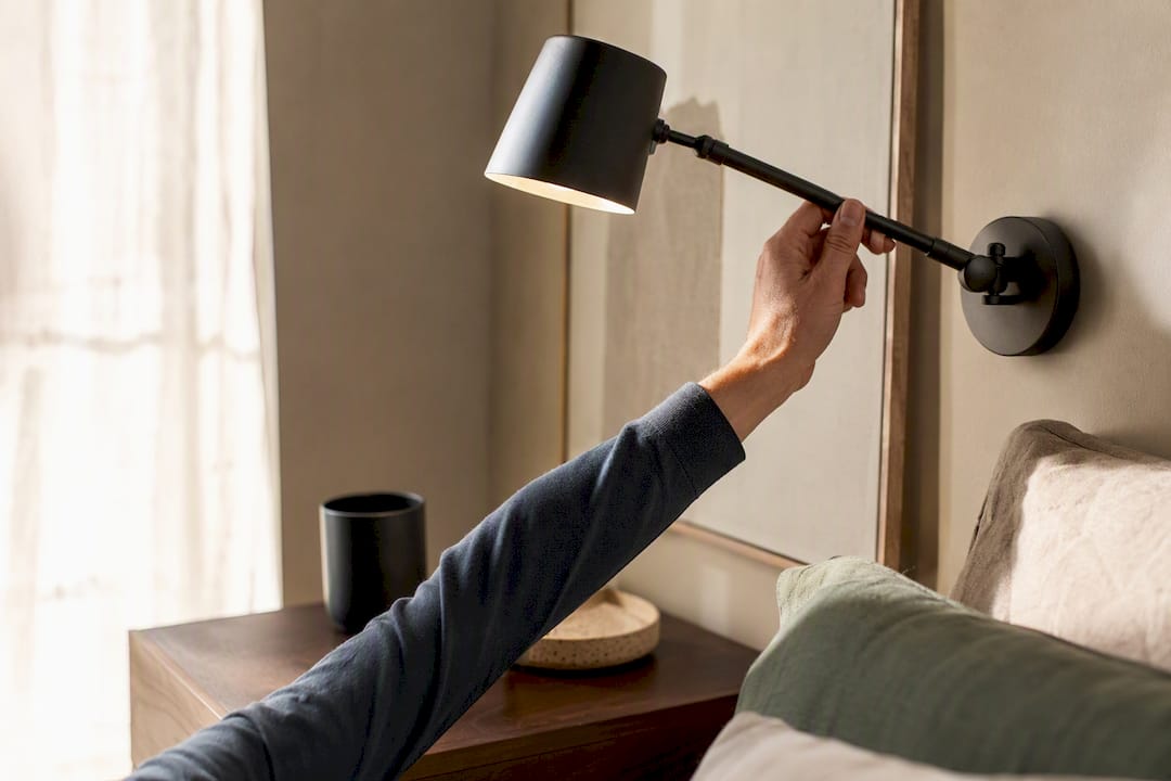 Hand adjusting bedside wall sconce swing arm