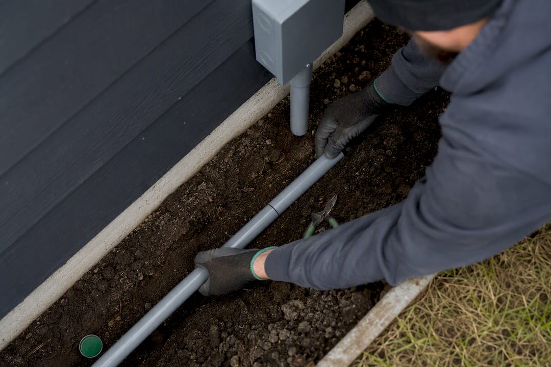 Electrician routing conduit in outdoor trench