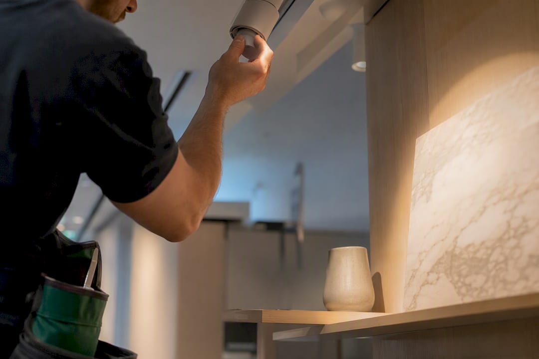 Installer aiming track light at display