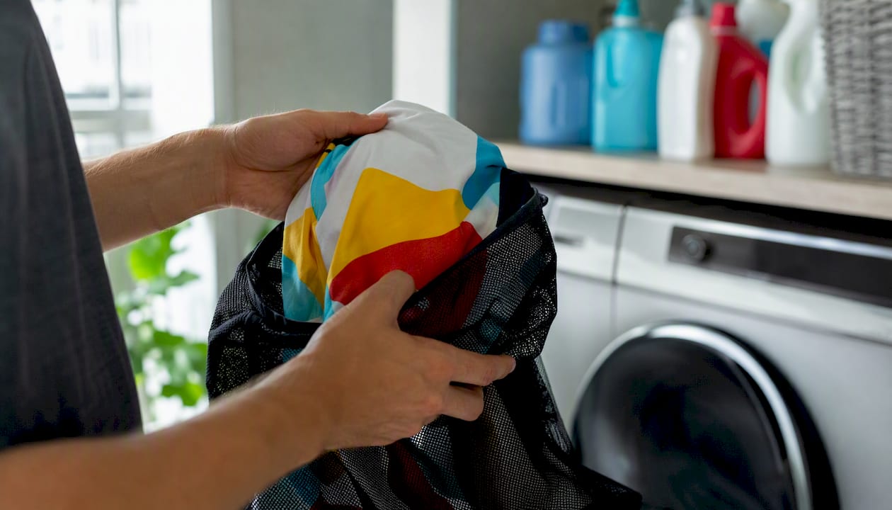 Hands putting combed cotton T-shirt into laundry bag