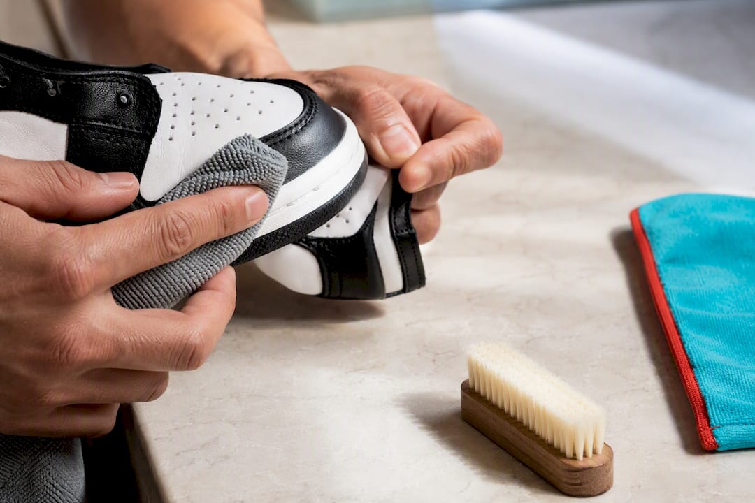 Hands wiping white sneaker leather panels