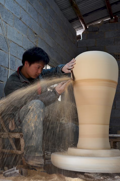 Hands cleaning a narrow vase with rice