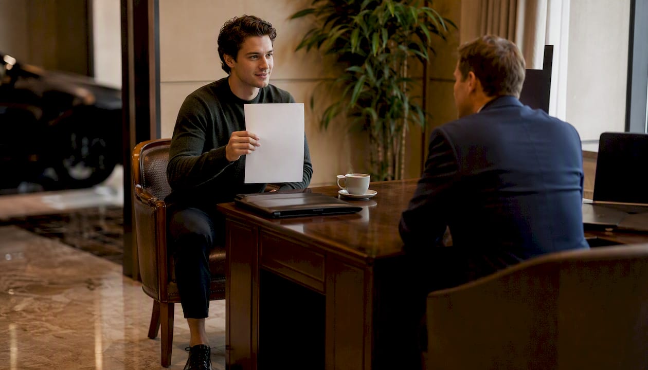 Hands exchanging pre-approval letter at car dealership desk