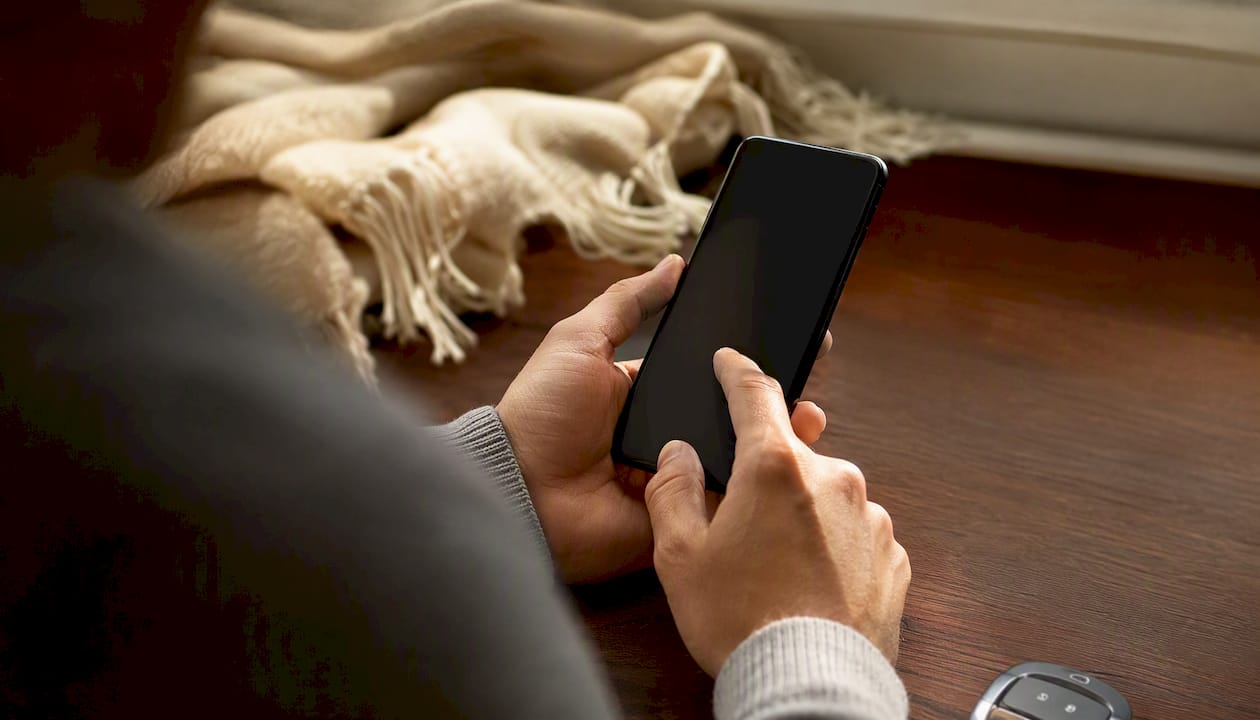 Hands holding smartphone with dark screen