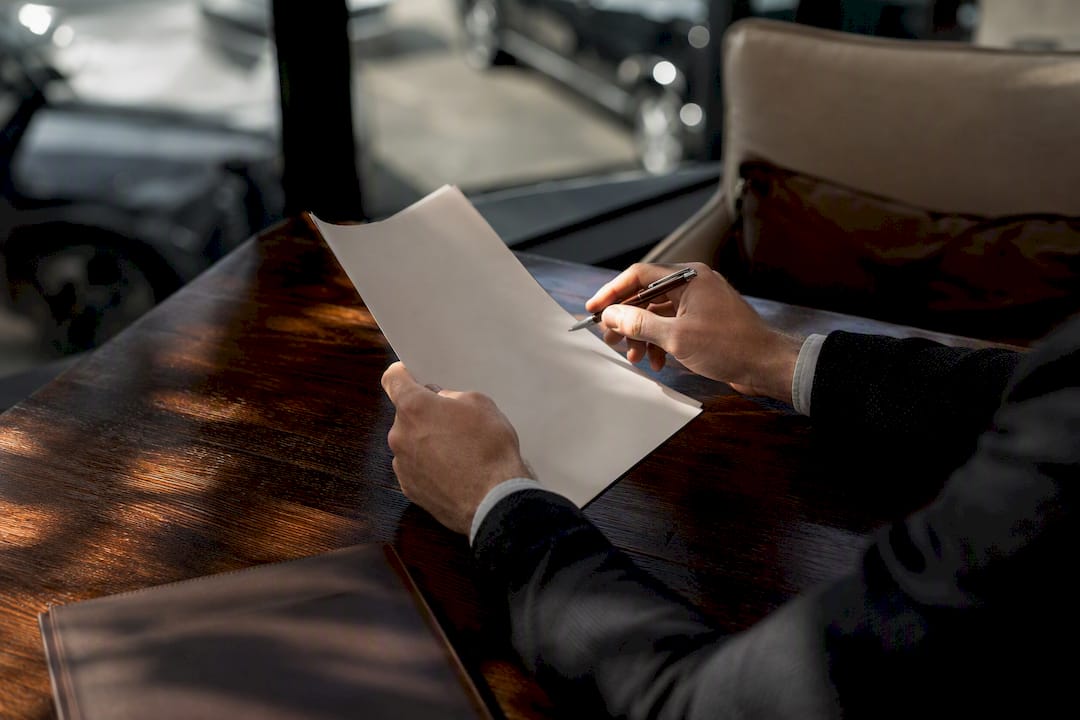 Hands holding finance document at dealership desk
