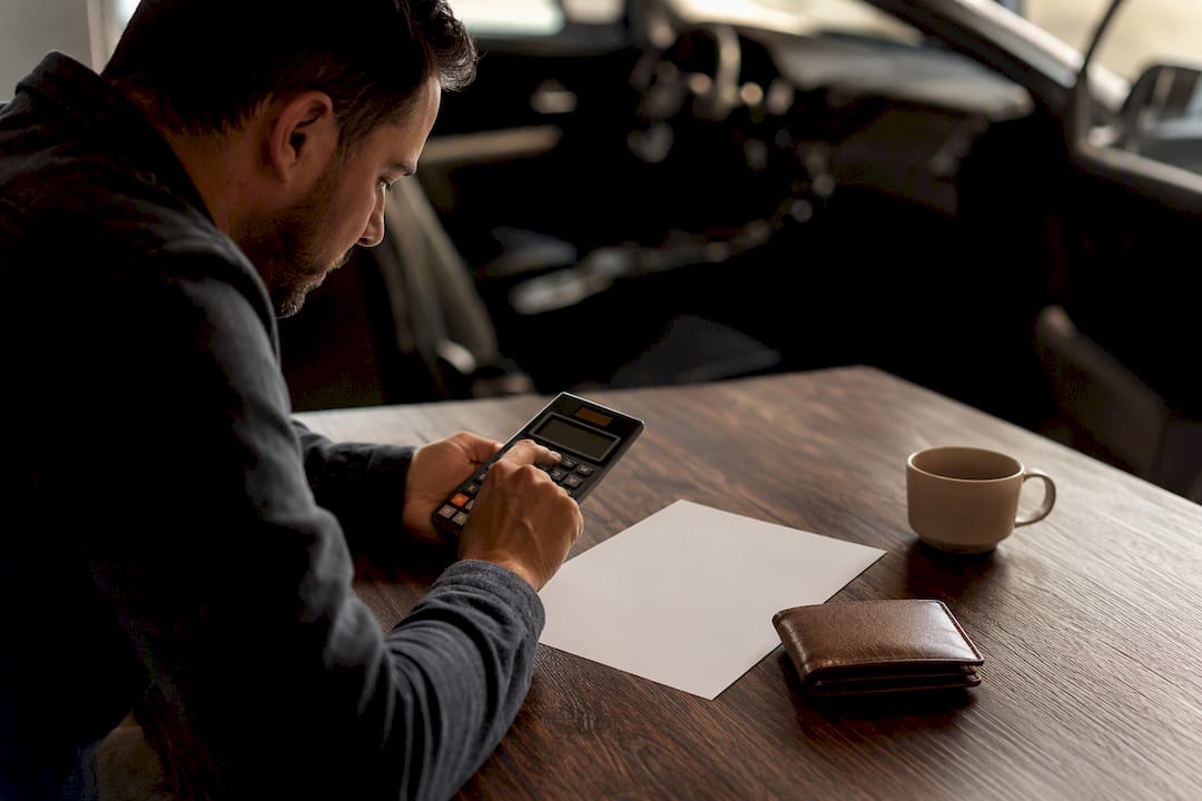 Hands calculating auto loan interest with calculator