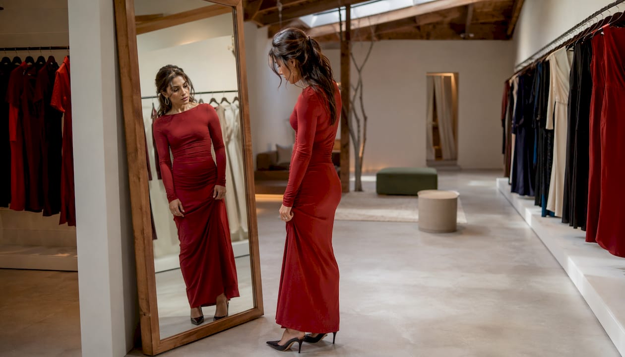 Woman testing fit of long sleeve dress seated
