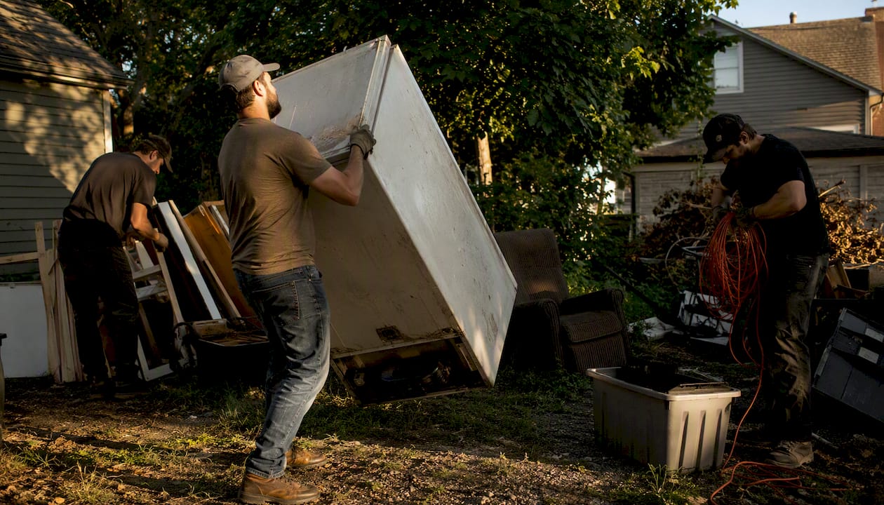 Junk removal team loading household junk in driveway