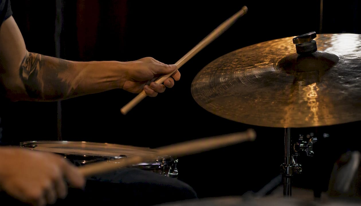 Drumsticks striking cymbals in live setting