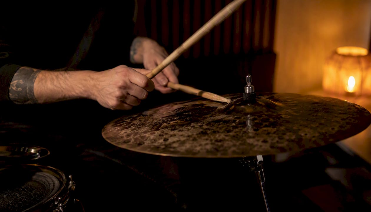 Close hands playing dark cymbal in warm studio