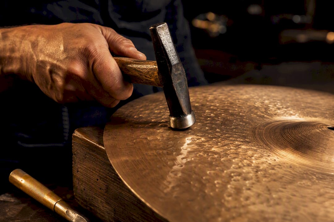 Artisan hammering a cymbal surface