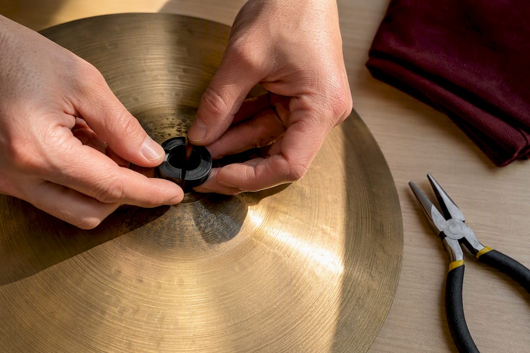 Hands fitting grommet into cymbal hole