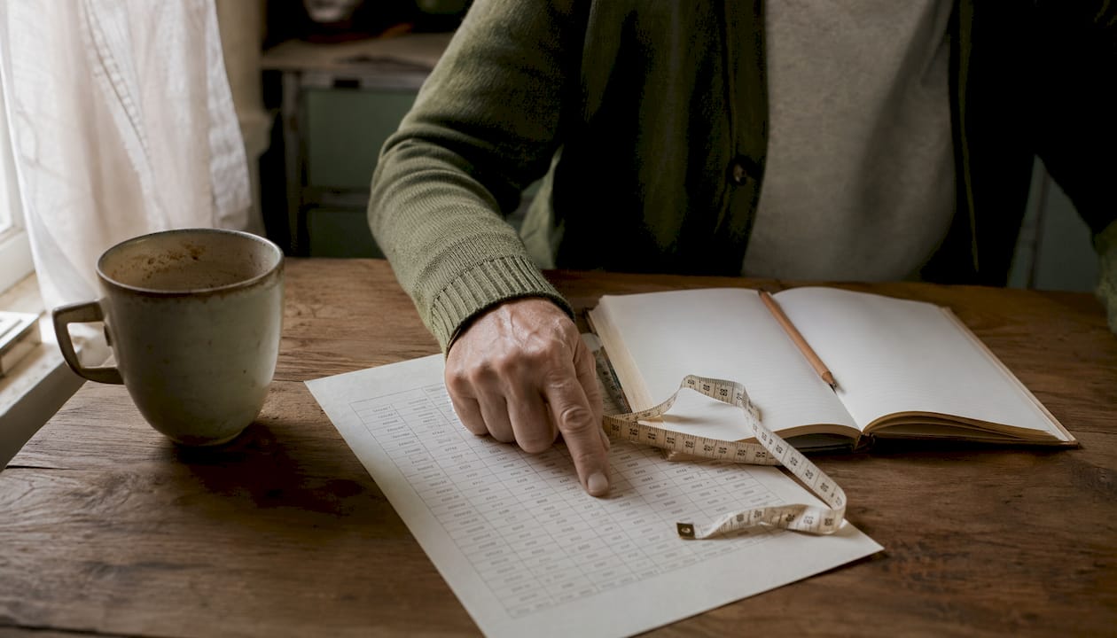 Hands pointing at hat size chart on table