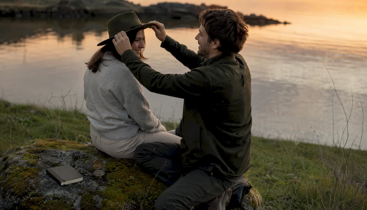 Man adjusting beanie fit on woman outdoors