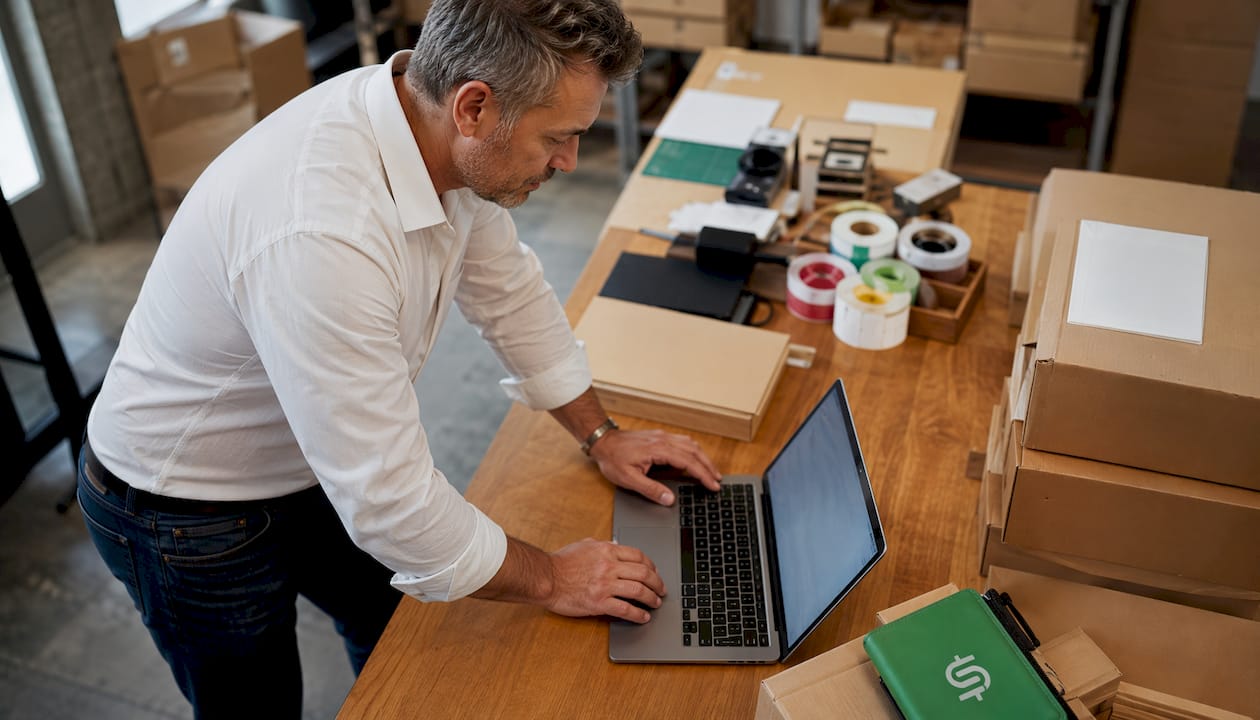 Man managing eBay shipping profiles in warehouse office