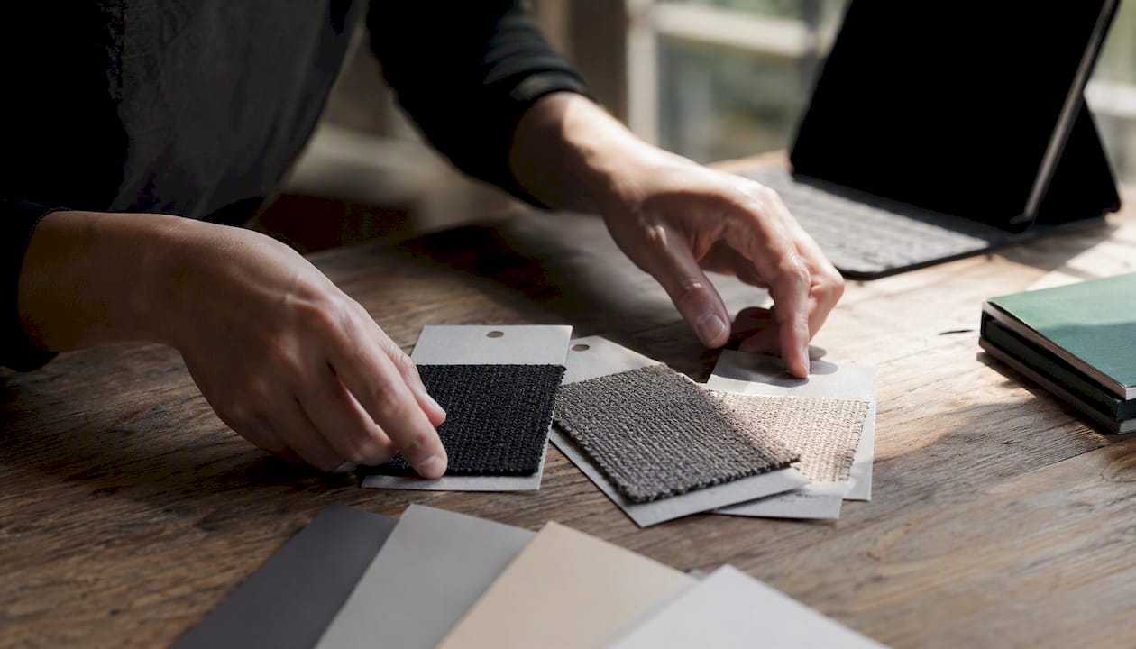 Hands arranging fabric swatches for listing variations