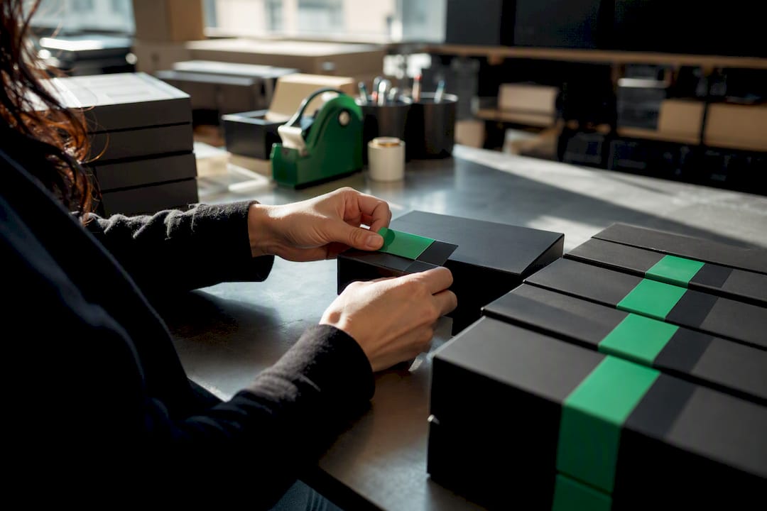 Hands applying attribute tags on product boxes