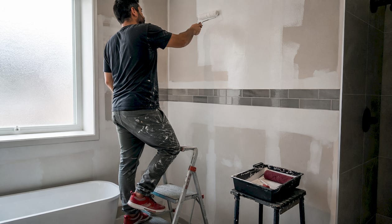 Painter applying semi-gloss paint in bathroom