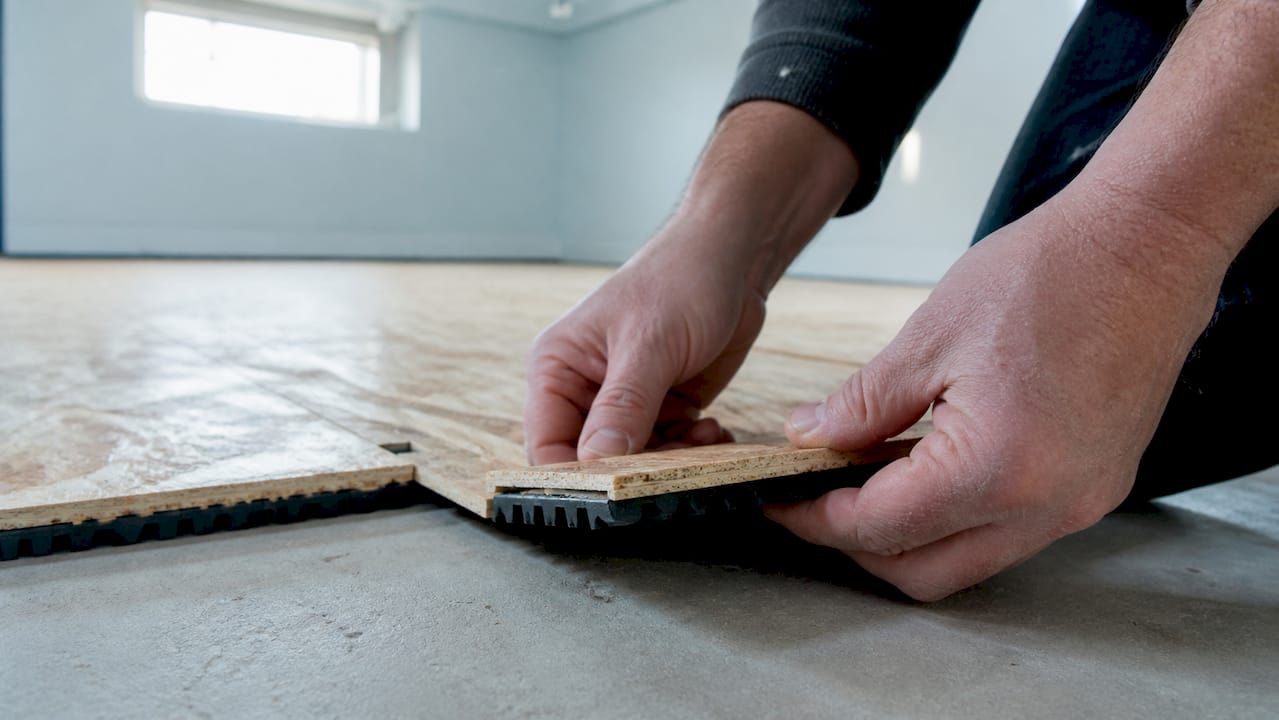 Hands joining interlocking basement subfloor panels