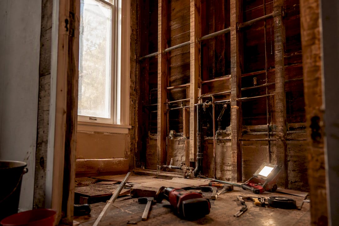 Exposed plumbing and framing in older bathroom wall