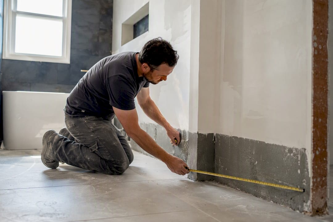 Installer measuring bathroom wall angle before tiling