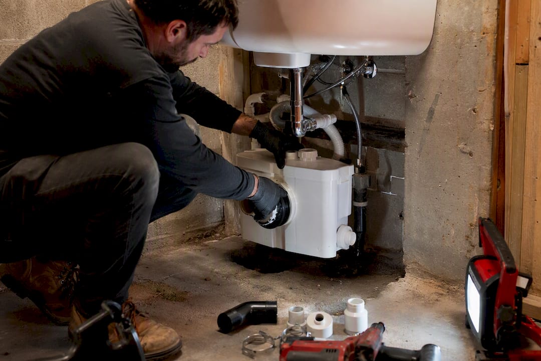 Hands installing macerator pump under sink