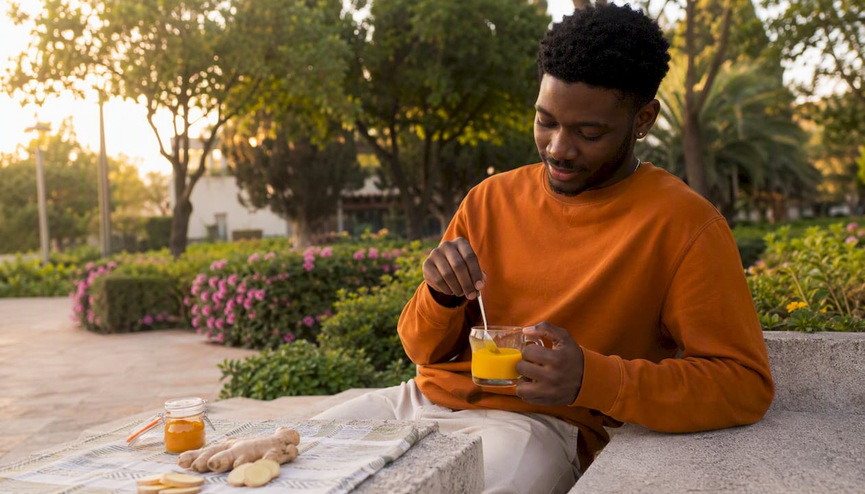 Young man stirring turmeric-ginger tea in café