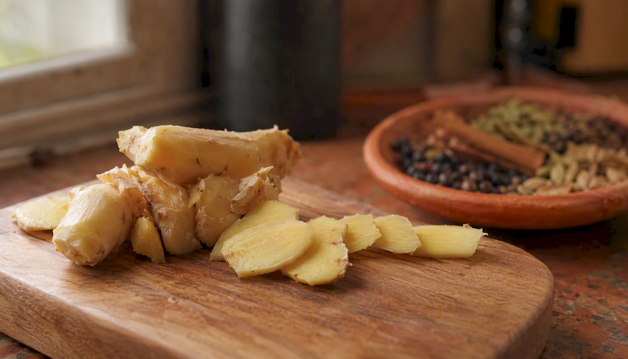 Fresh ginger root and slices on board