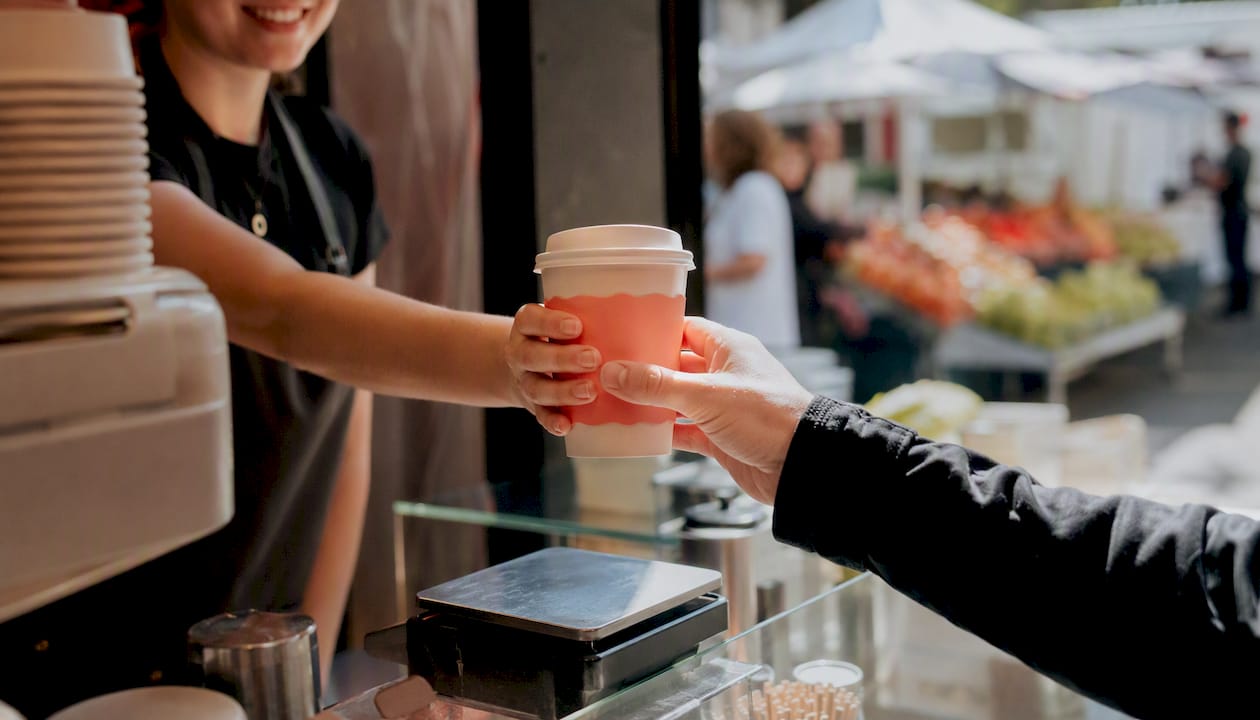Handing over grab-and-go chai cup at kiosk