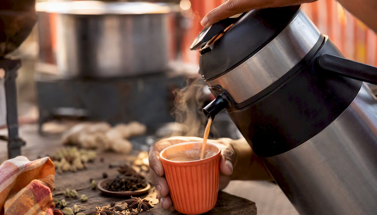 Masala chai pouring from insulated airpot at pop-up stall