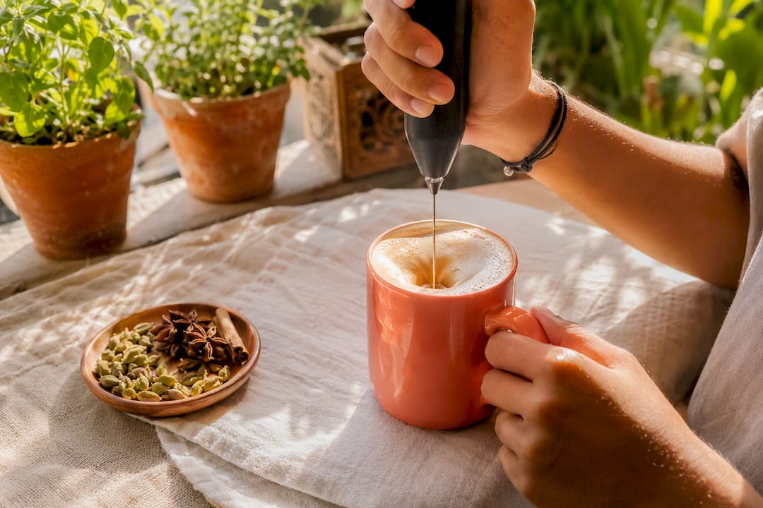 Hand frothing vegan chai latte with plant milk
