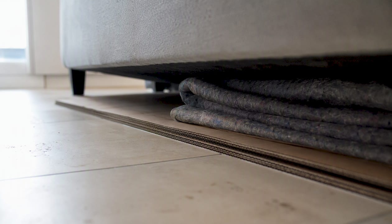 Un carton de protection et un tissu sont placés sous l’assise du canapé pour garantir sa durabilité et préserver le confort.