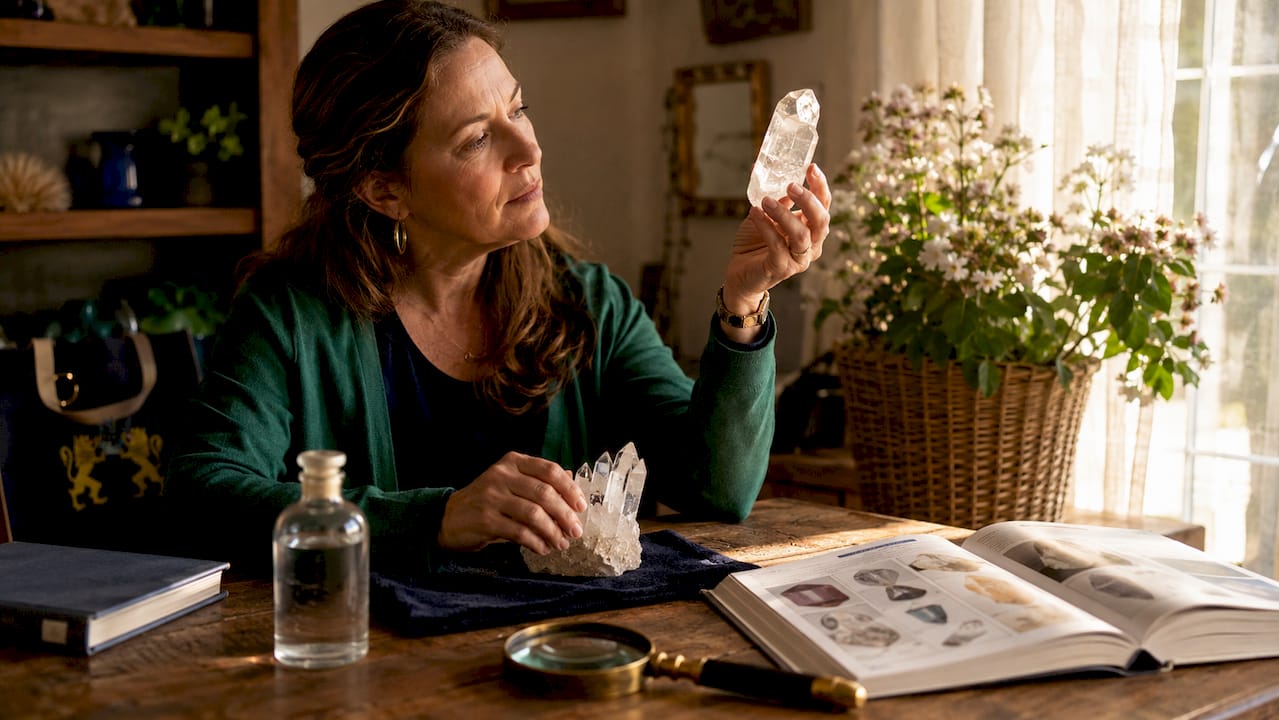 Woman inspecting crystals under warm lamp light