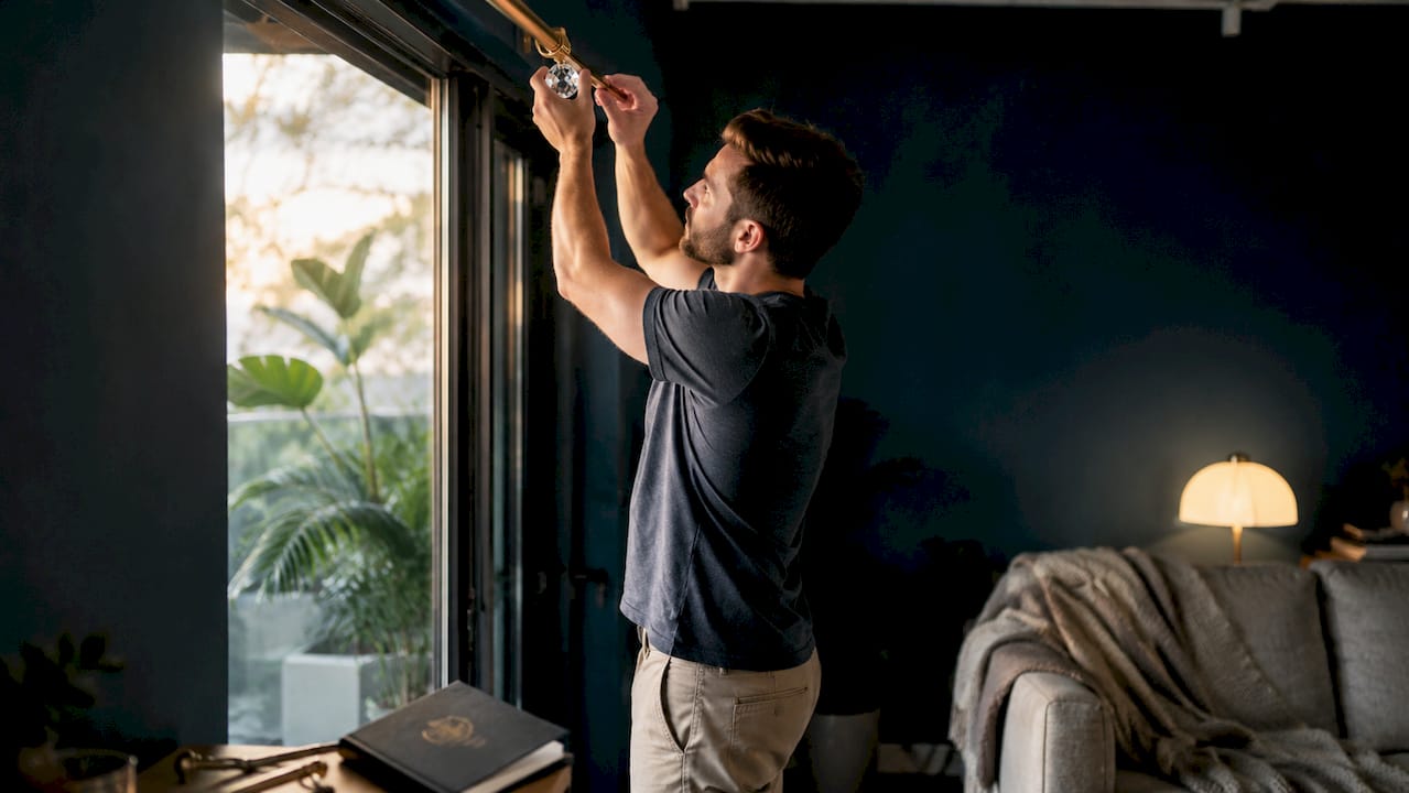 Man fixing crystal finial on curtain rod