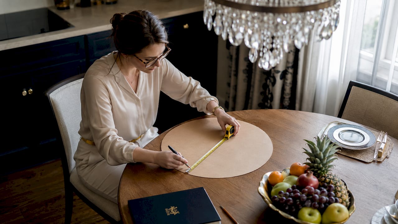 Woman sizing chandelier diameter over dining table