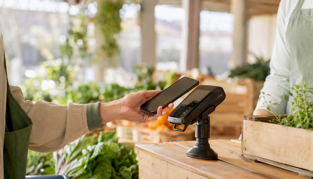Hand holding phone tapping payment terminal