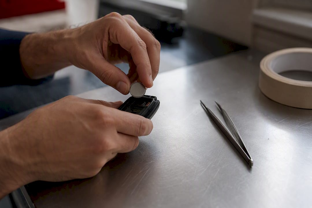Hands placing a coin cell battery inside key fob