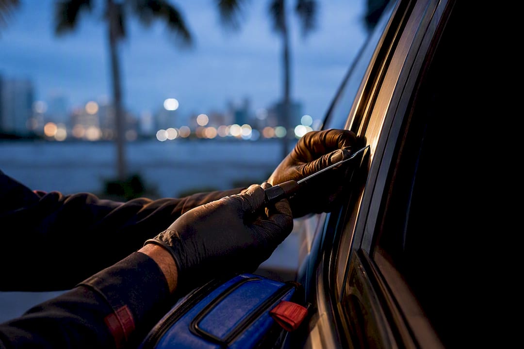Locksmith using entry tool beside locked vehicle door
