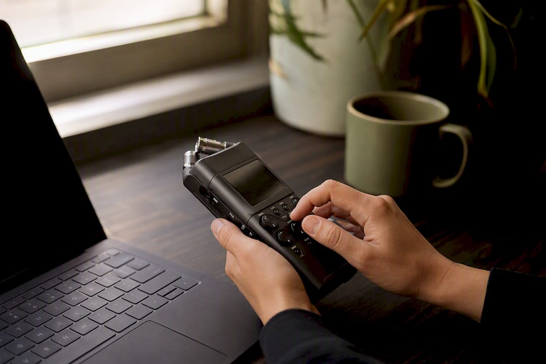 Hands pressing record on audio recorder