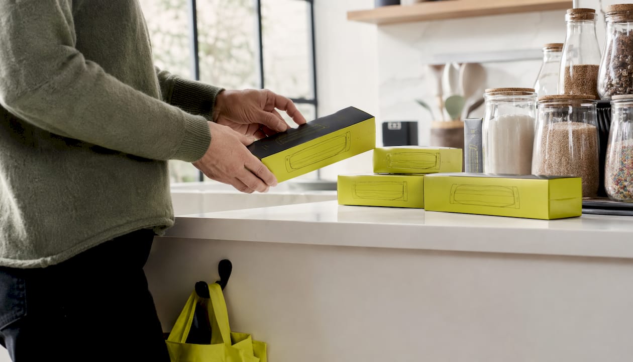 Hands retrieving compostable bag box from pantry shelf