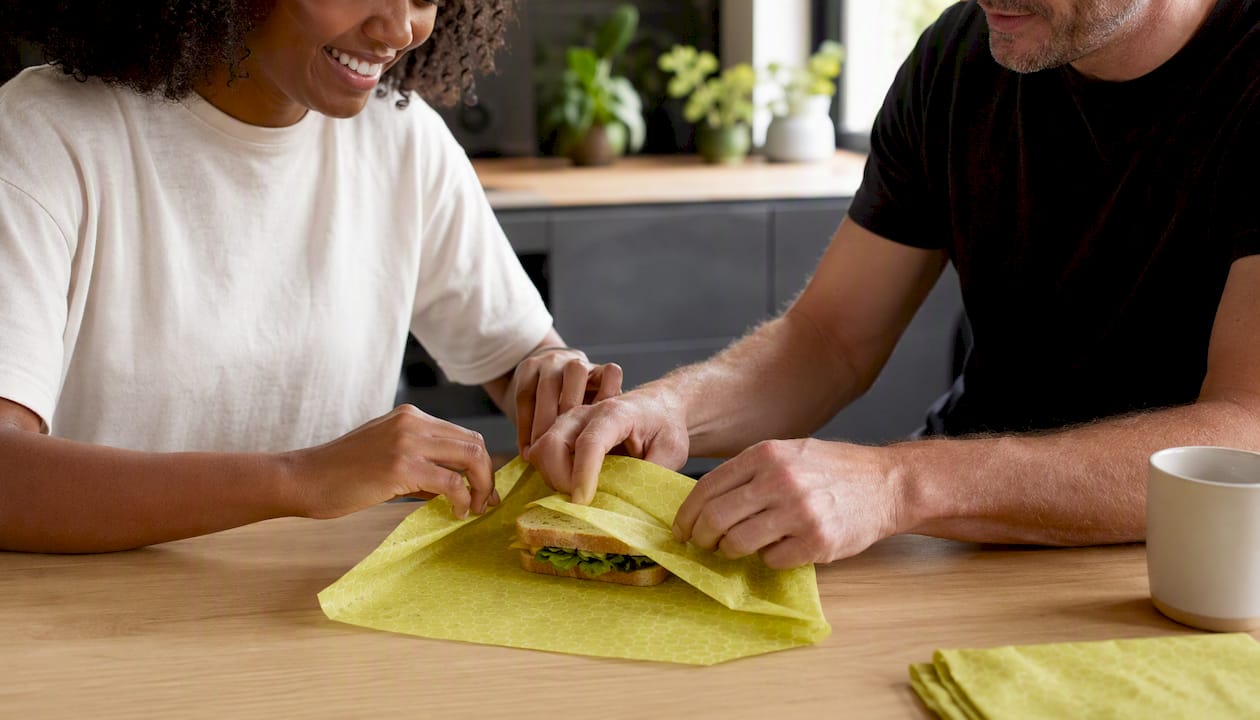 Hands wrapping sandwich with beeswax wrap