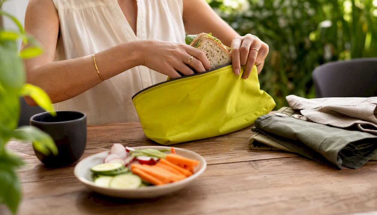 Hands packing sandwich into reusable zip bag