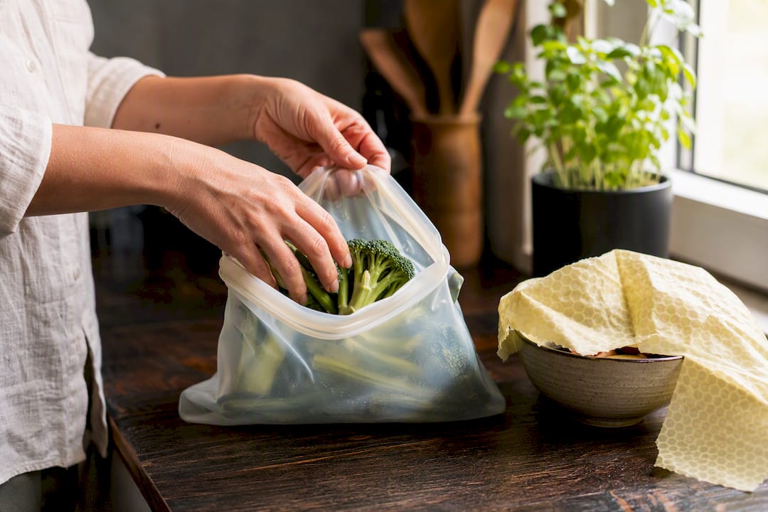 Hand sealing silicone bag and beeswax wrap on kitchen counter