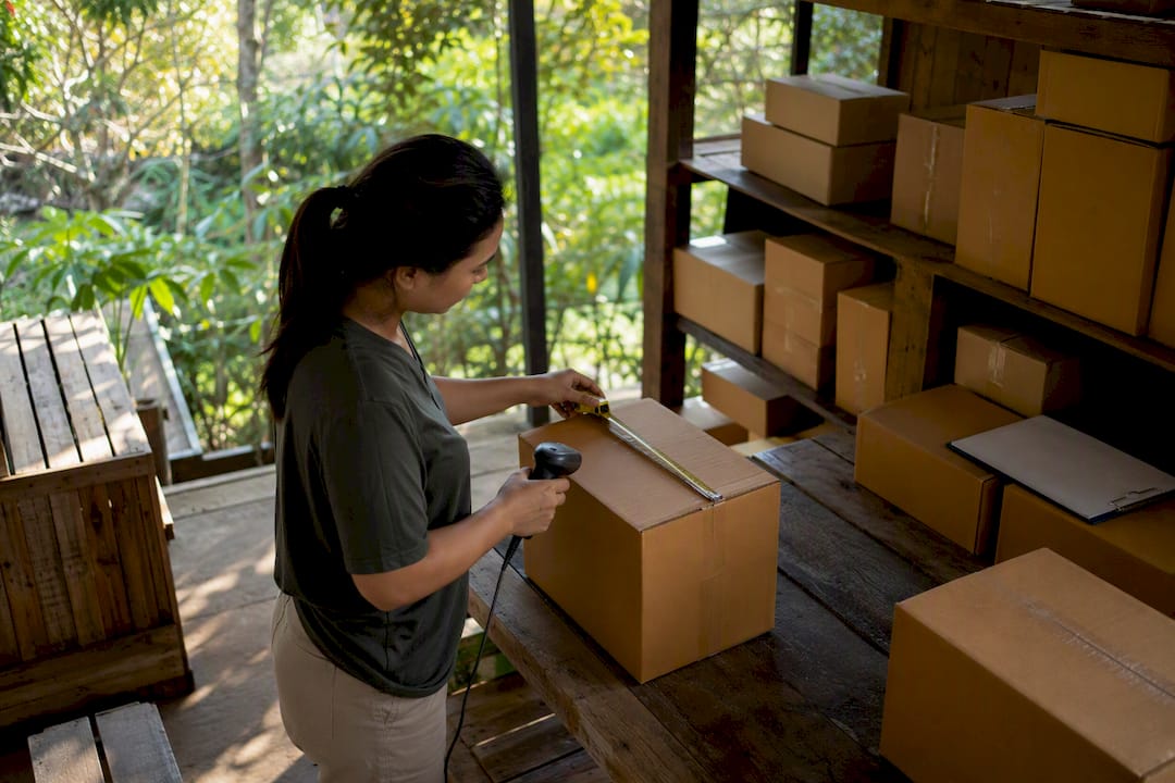 Hands measuring inventory boxes in storage