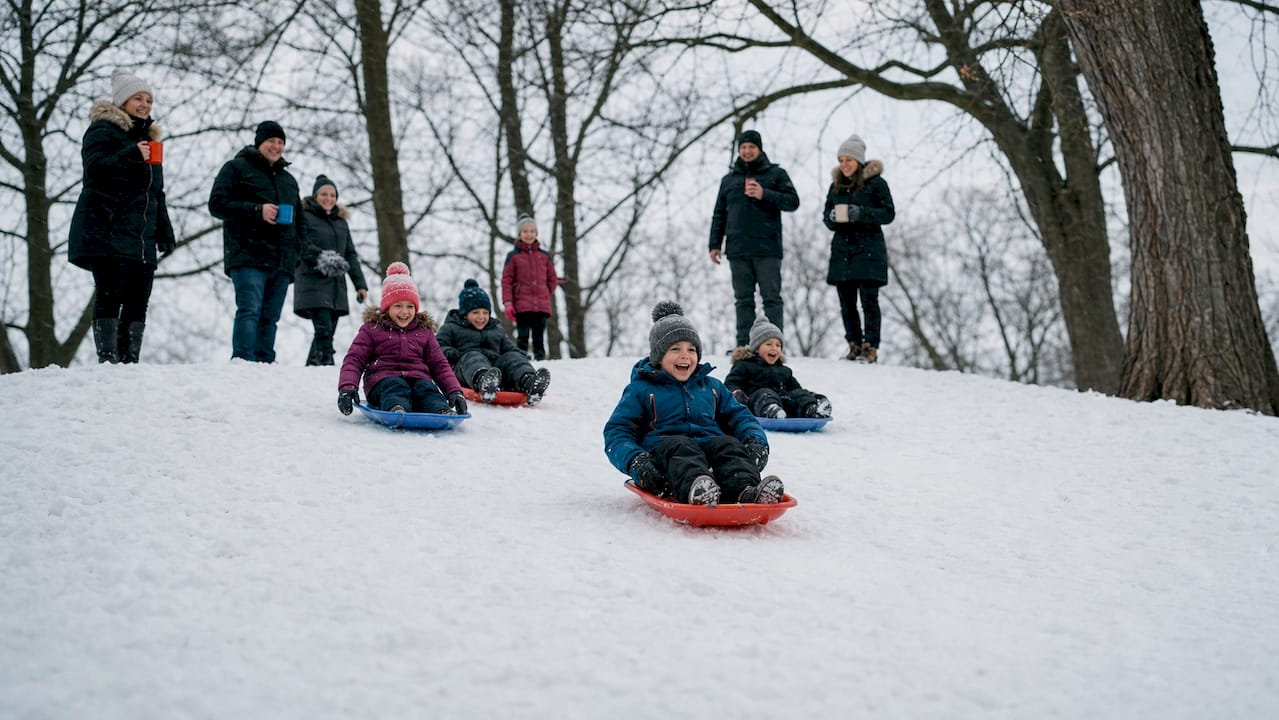 Children tobogganing down snowy hill