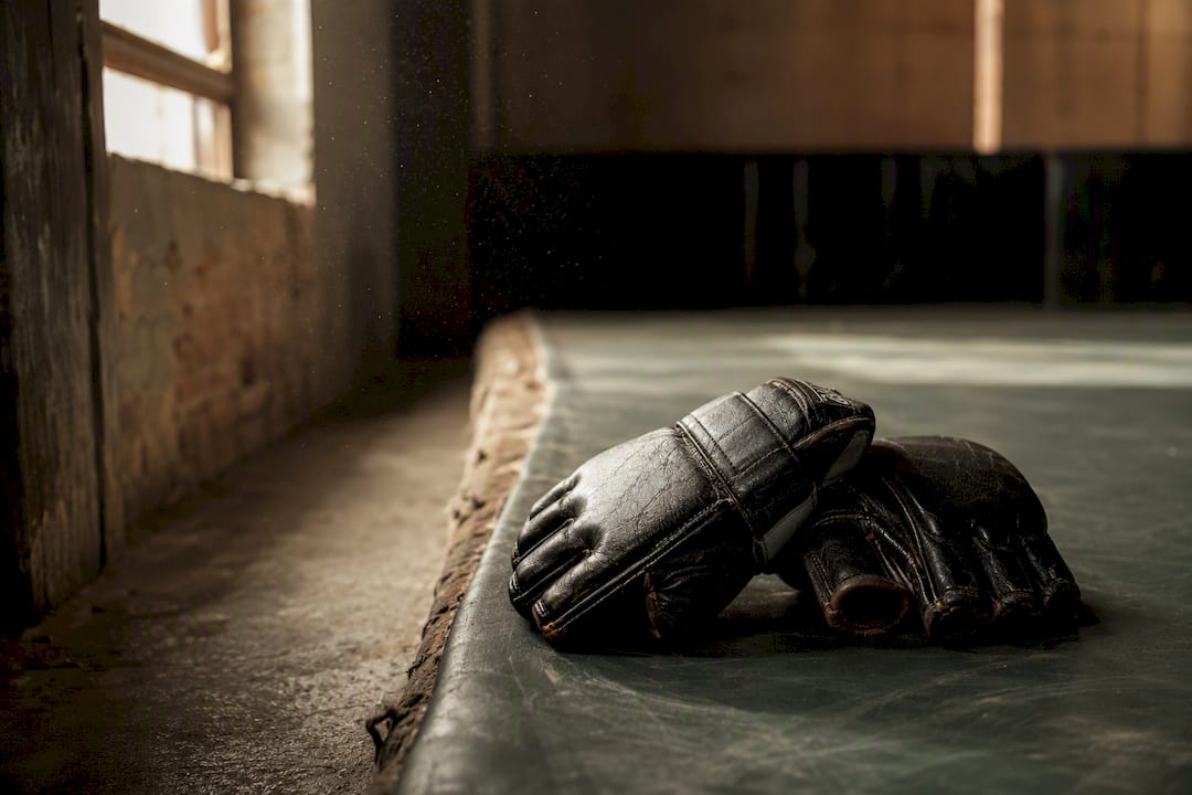 Worn MMA gloves on edge of wrestling mat